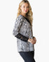 A woman modeling a long-sleeve top with a black and white snakeskin pattern and black lace cuffs, paired with dark jeans, against a plain white background.