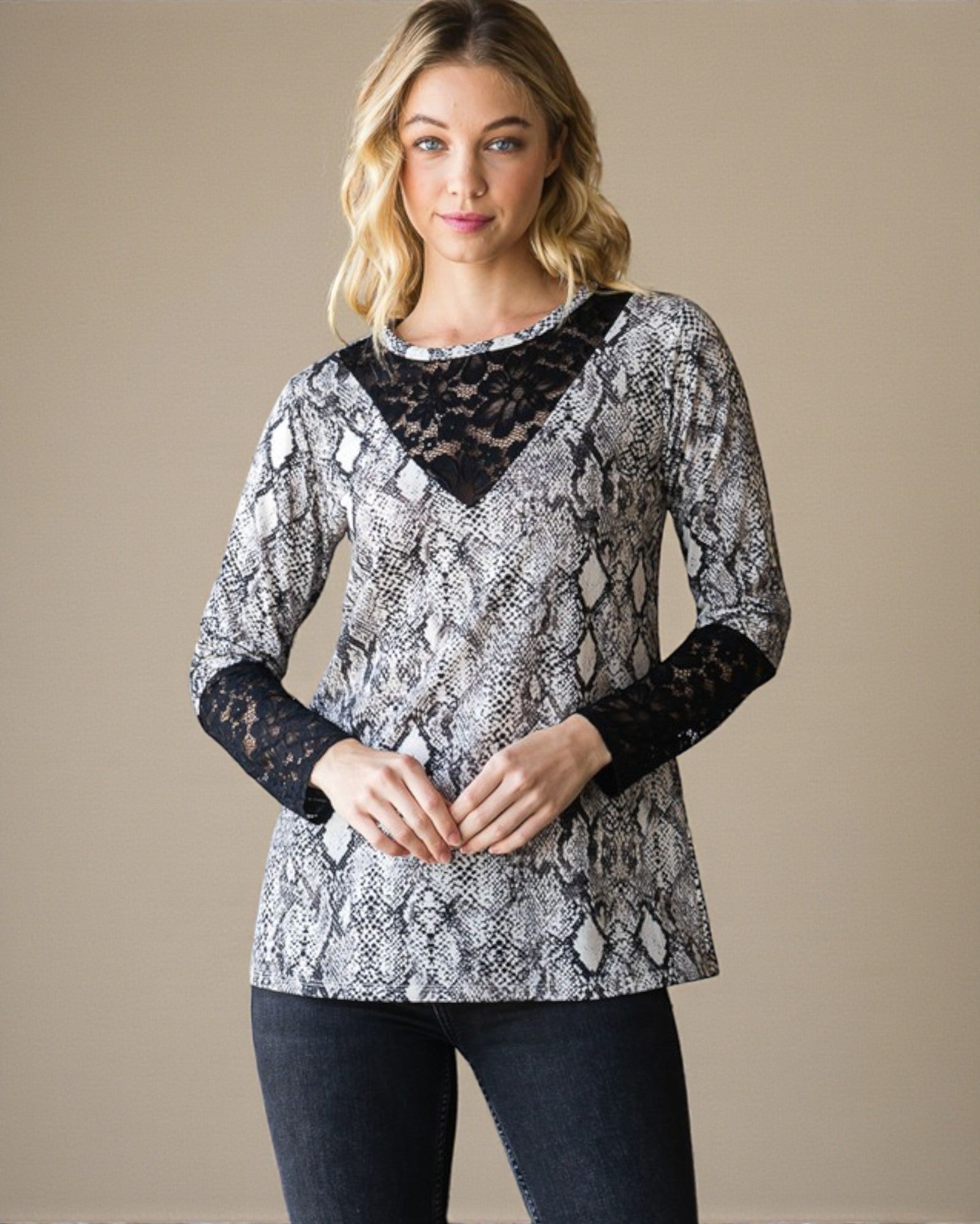 Woman wearing a snake print top with black lace sleeves on a beige background