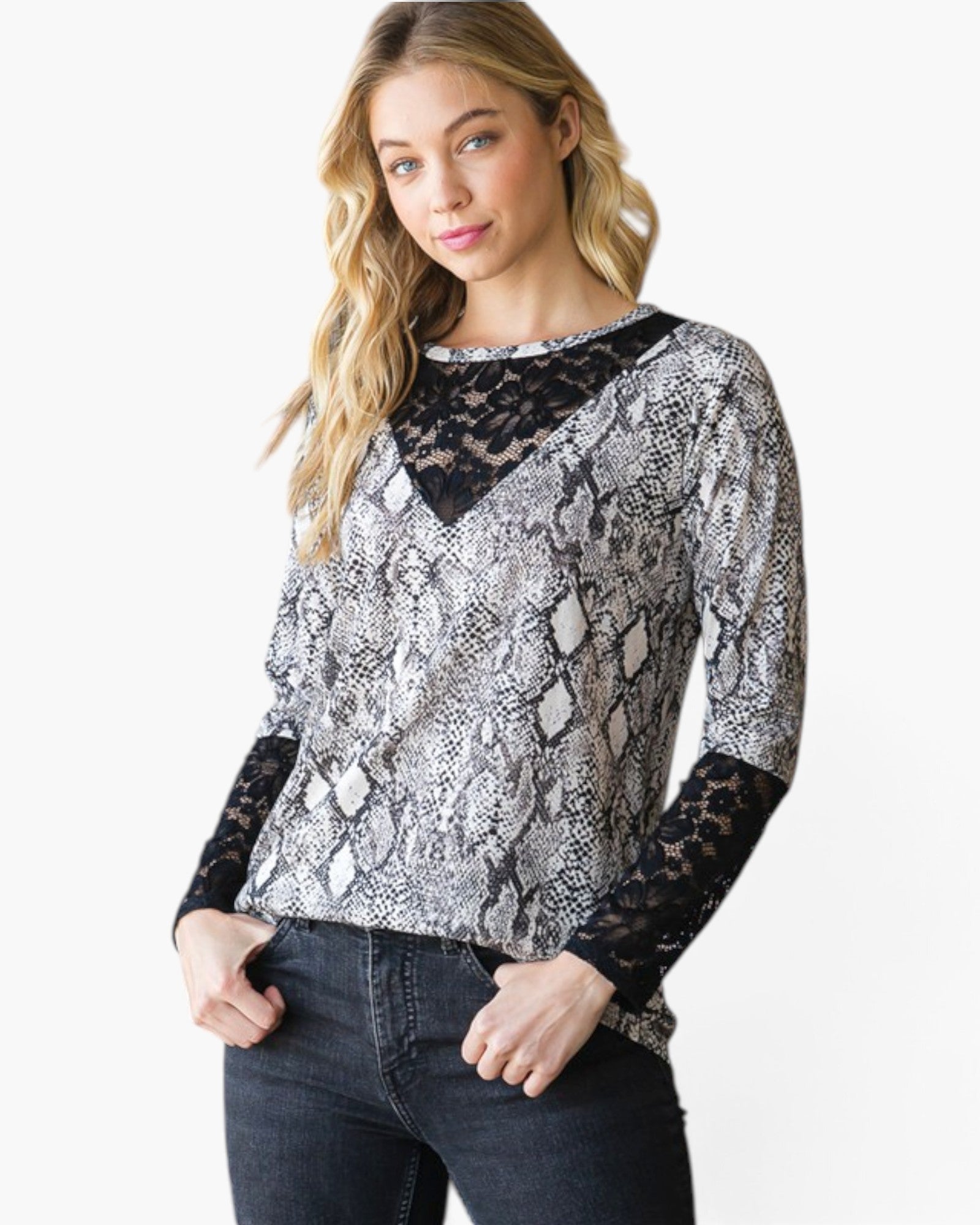 A woman modeling a long-sleeve V-neck top featuring a black and white snakeskin pattern with solid black lace sleeves and a black lace V-neckline overlay, paired with dark wash jeans against a plain white studio background.