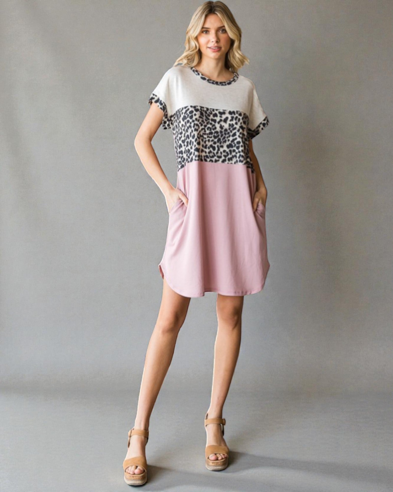 Woman wearing a dress with a leopard print top and pink skirt on a gray background