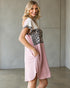 Woman wearing a pink dress with a leopard print top against a neutral background