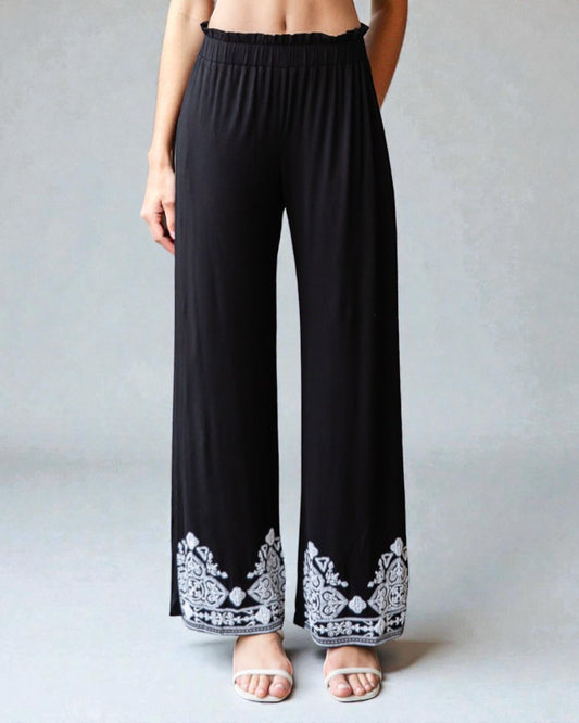 Black wide-leg pants with white lace detailing on a plain background
