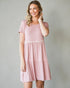 Woman wearing a pink dress with a white waistband against a gray background