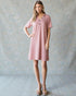 Woman wearing a pink dress against a plain background