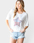 Woman wearing a white t-shirt with a star design and denim shorts on a plain background