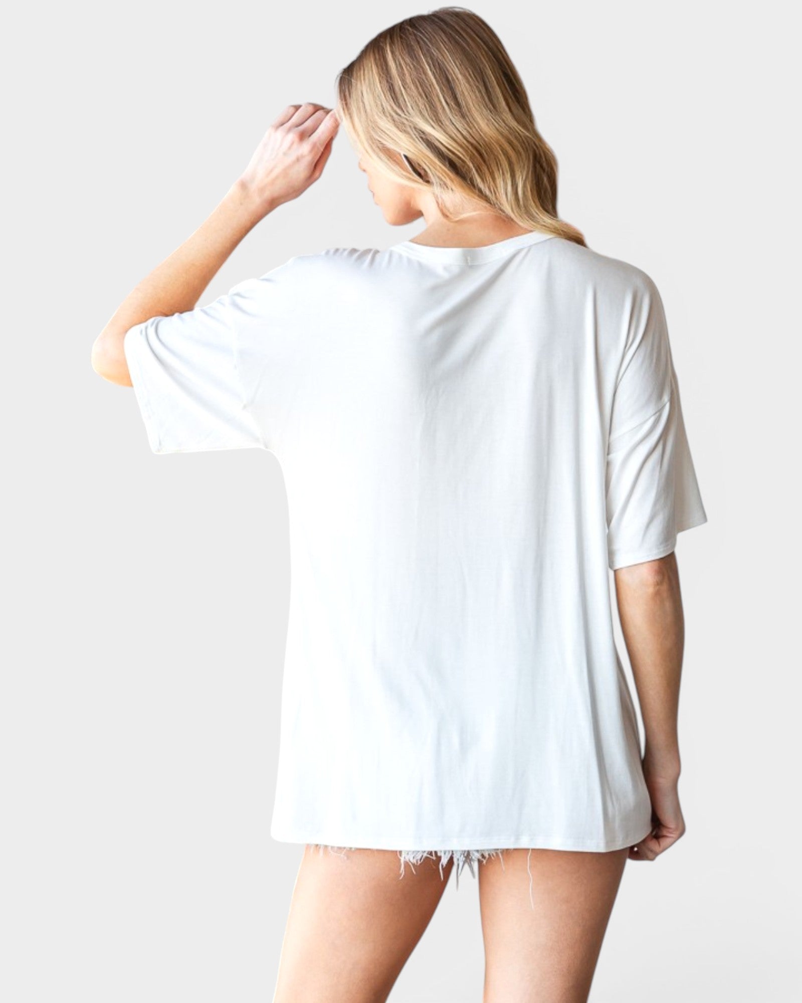 Woman wearing a white oversized t-shirt against a plain background