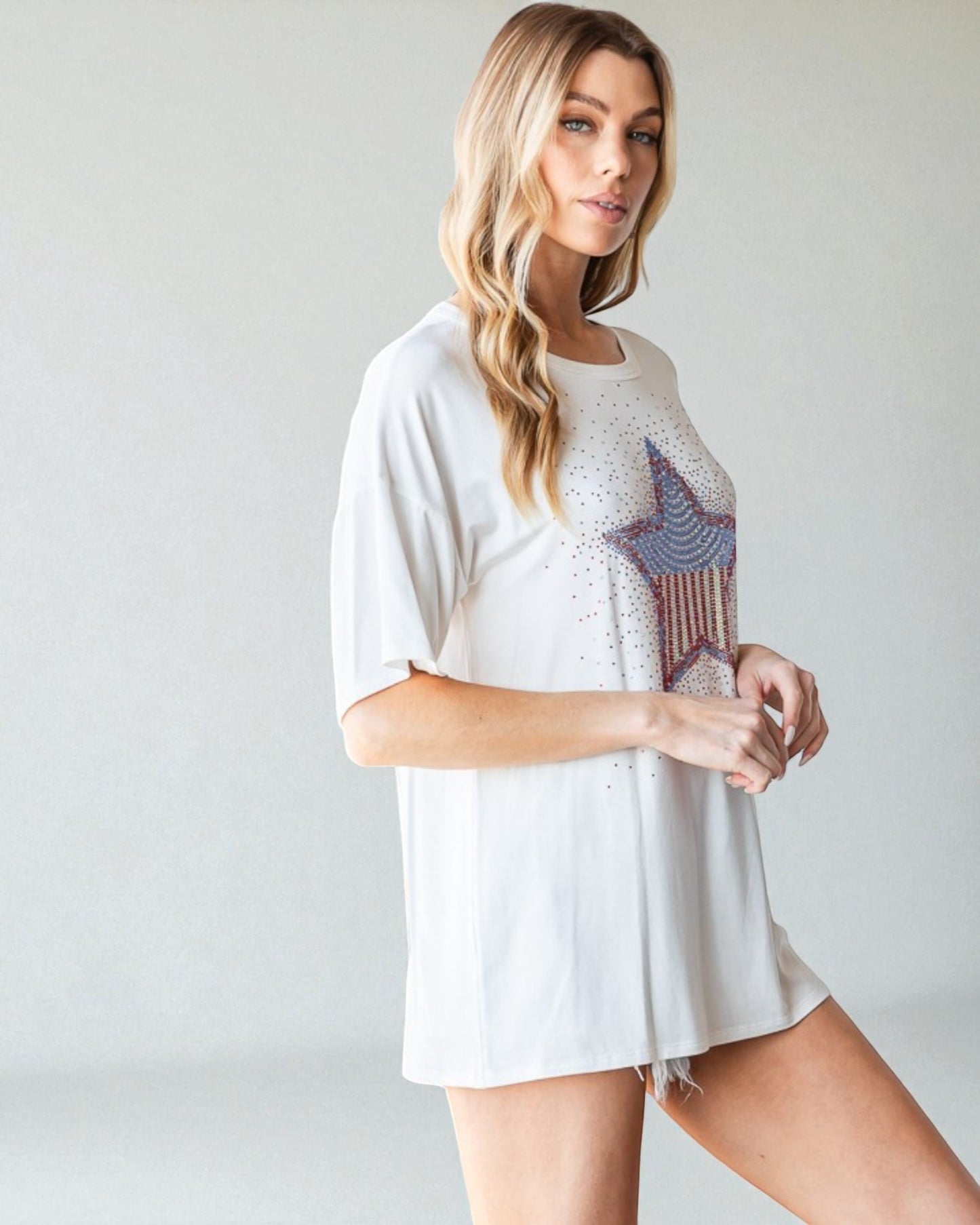 Woman wearing a white t-shirt with a star design on a plain background