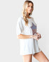 Woman wearing a white tunic with star designs on a plain background