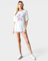 Woman wearing a white oversized t-shirt with a star design on a plain background