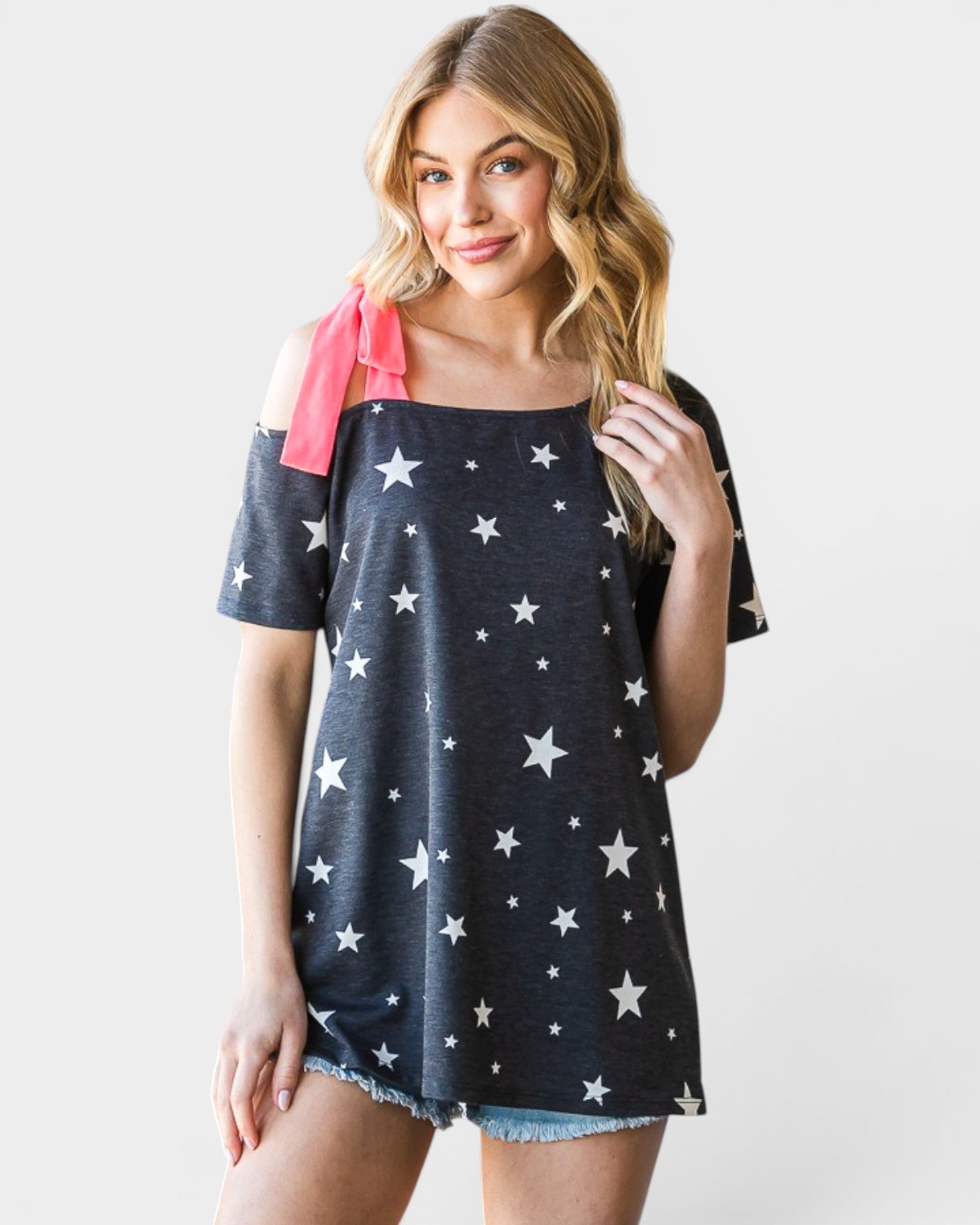 Woman wearing a navy blue off-shoulder top with white star patterns on a plain background