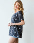 Woman wearing a navy blue t-shirt with white star patterns on a plain background
