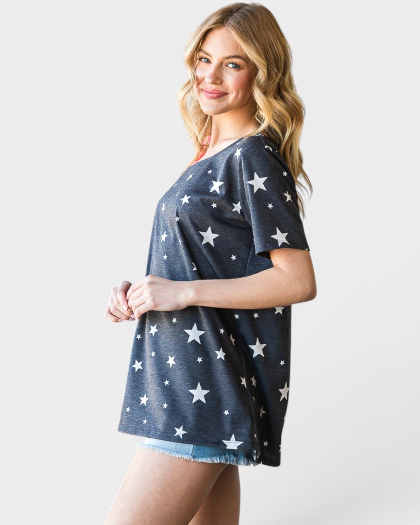 Woman wearing a navy blue t-shirt with white star patterns on a plain background