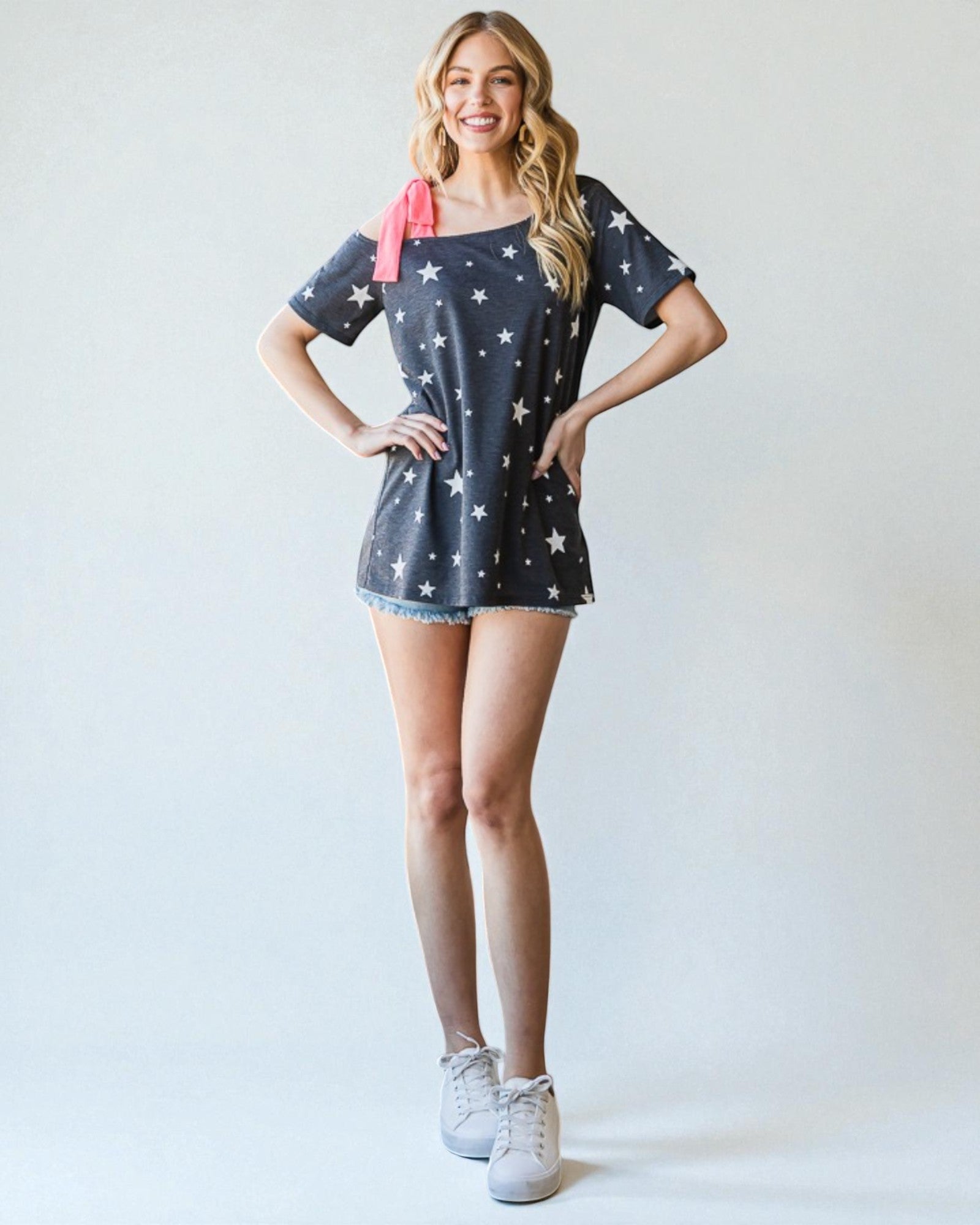 Woman wearing a star-patterned dress with a pink bow on a white background