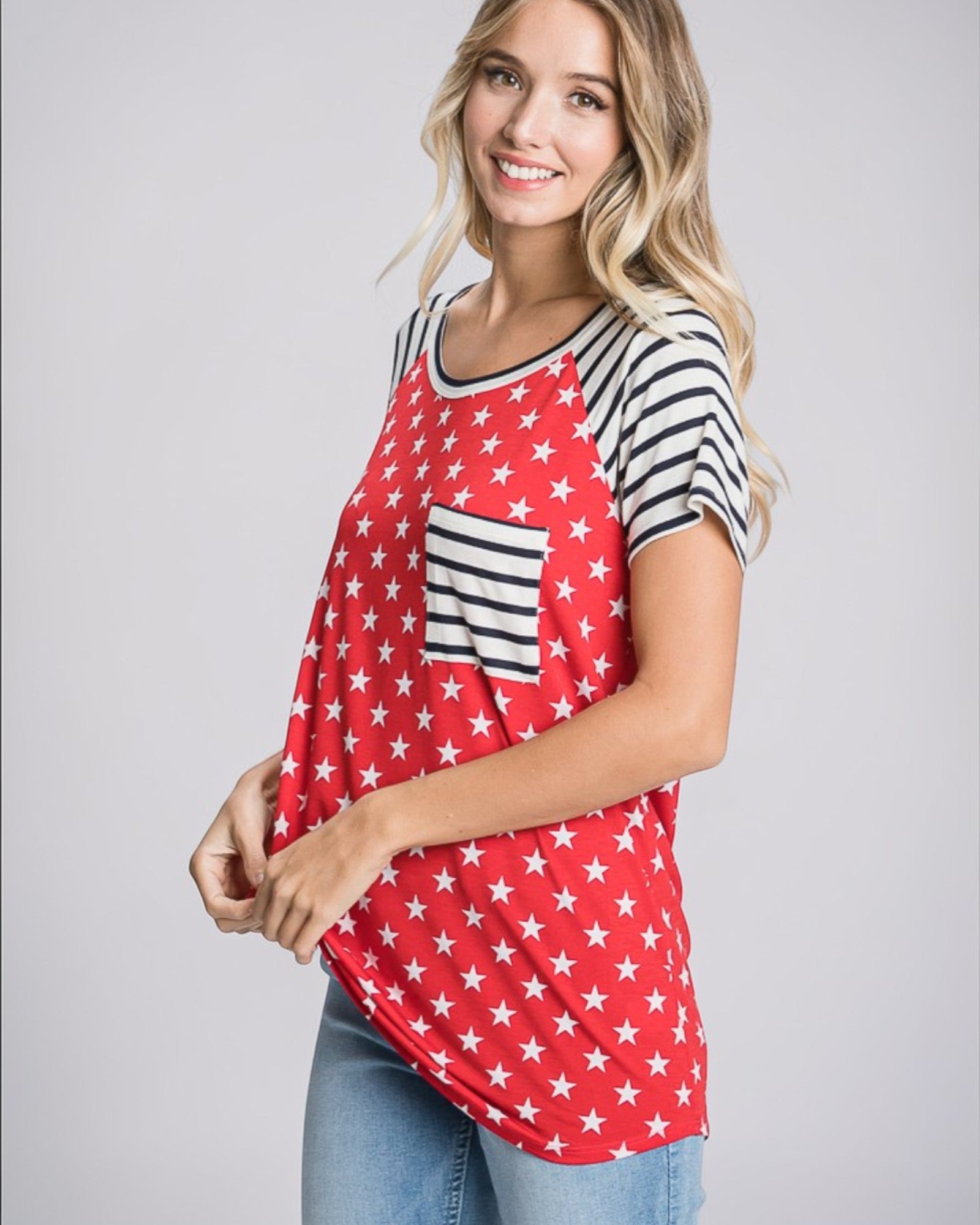 Woman wearing a red shirt with white star pattern and black and white striped sleeves on a gray background