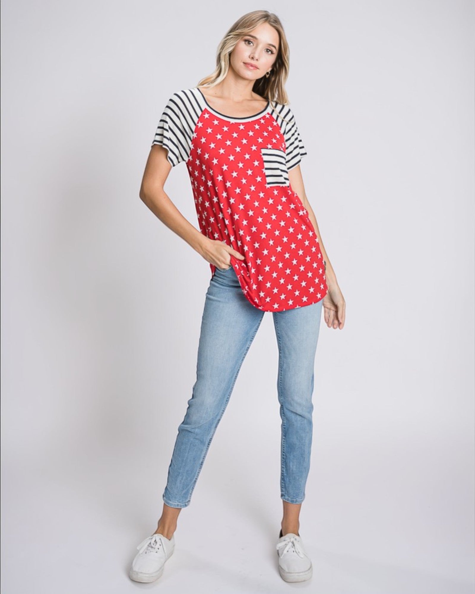Woman wearing a red polka dot shirt with black stripes and blue jeans on a white background