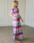 Woman wearing a colorful striped dress in a room with white paneled walls.