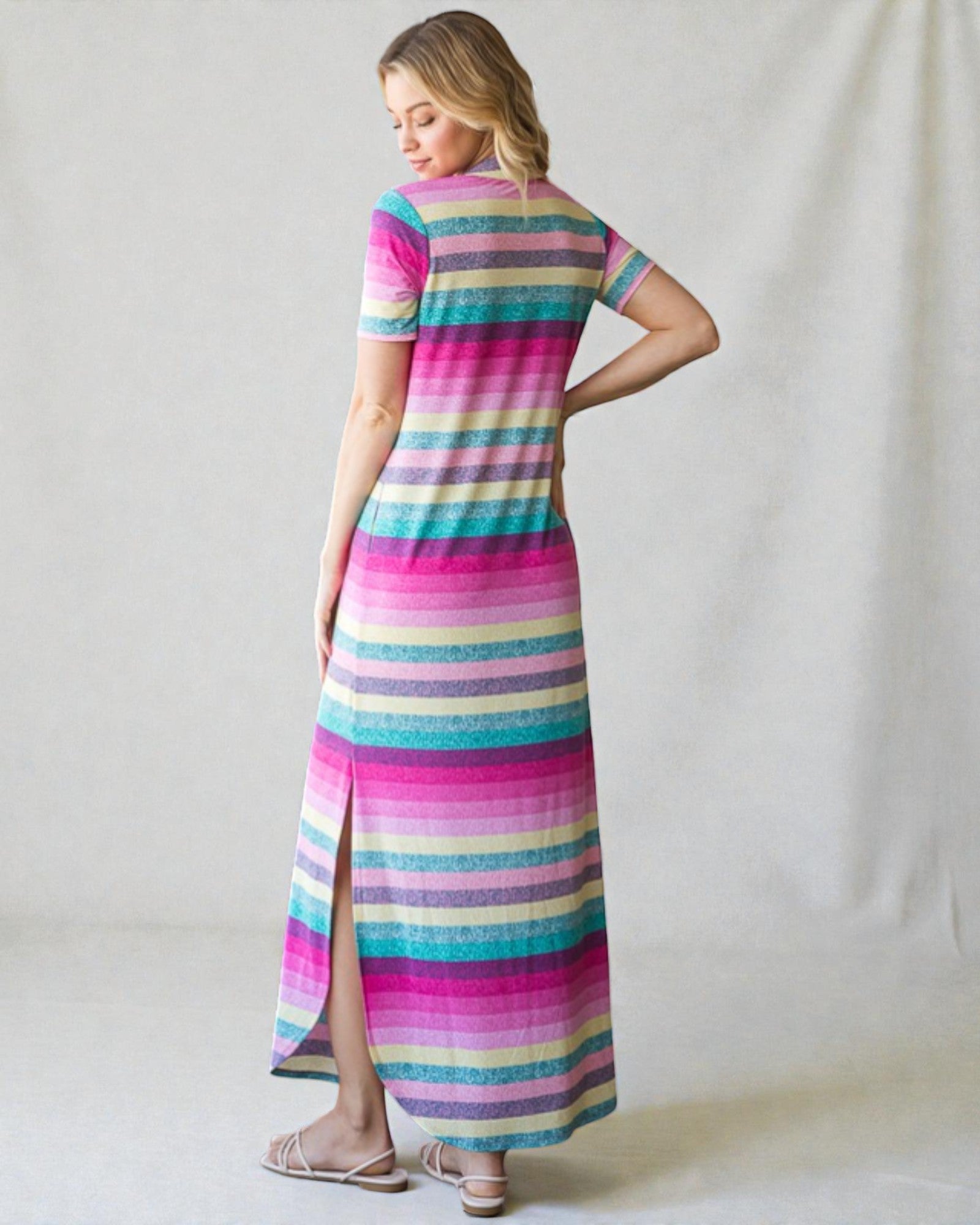 Woman wearing a colorful striped dress against a plain background