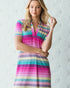 Woman wearing a colorful striped dress against a textured white background