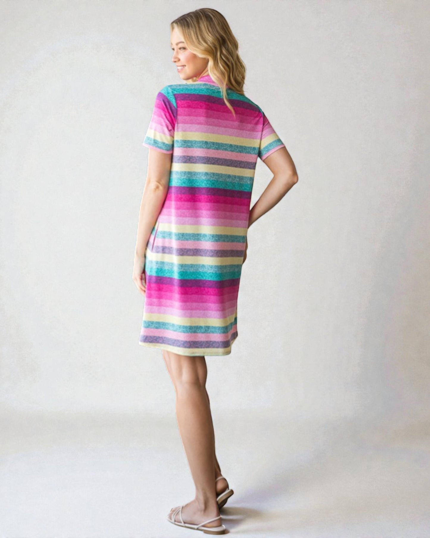 Woman wearing a colorful striped dress on a plain background