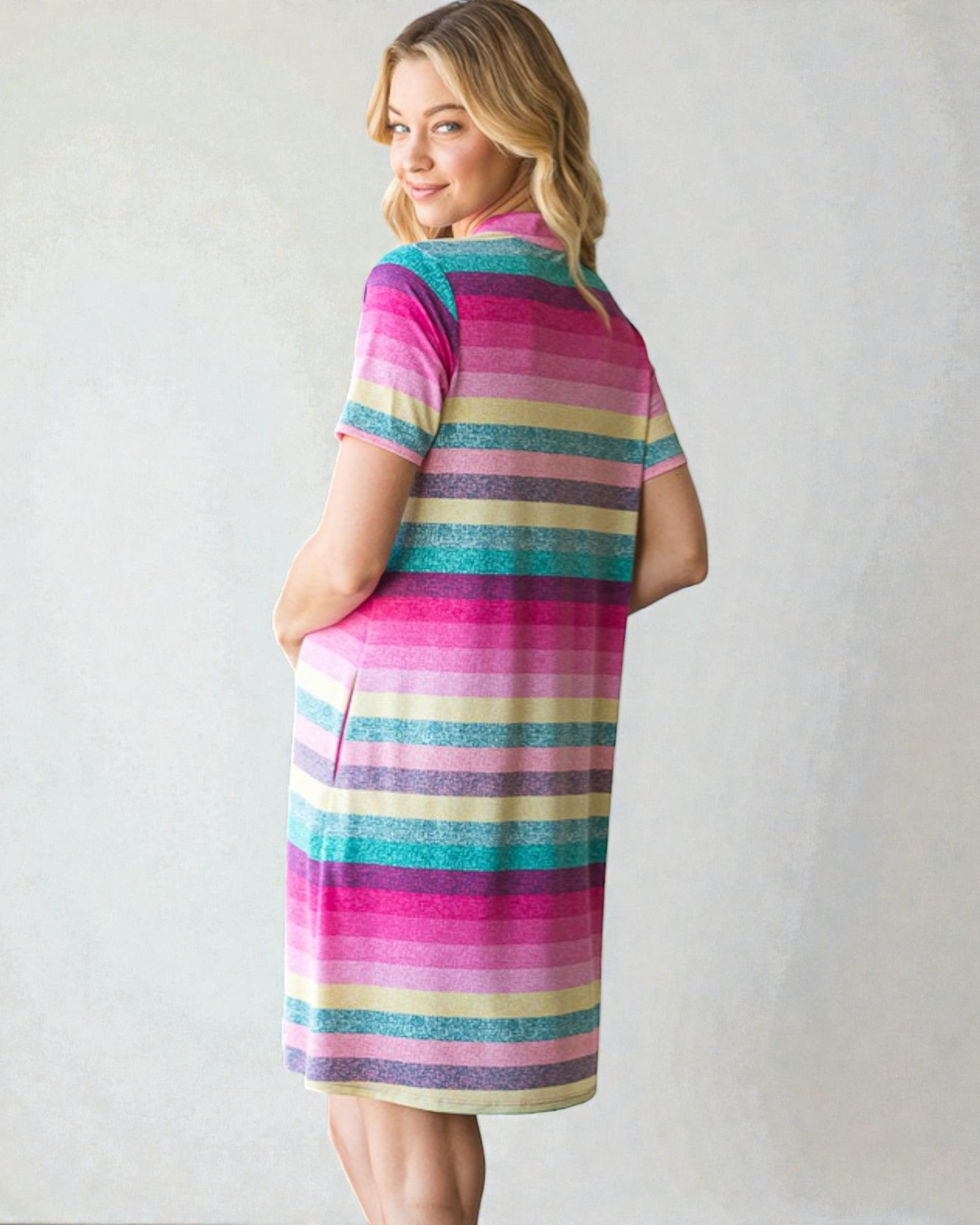 Woman wearing a colorful striped dress against a plain background