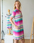 Woman wearing a colorful striped dress in a studio setting with a mannequin in the background.