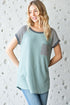 Woman wearing a green and gray patterned top against a textured white background