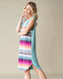 Woman wearing a colorful striped dress with a light blue cover-up against a beige background