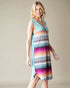 Woman wearing a colorful striped dress against a plain background