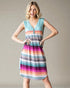 Woman wearing a colorful striped dress against a plain background