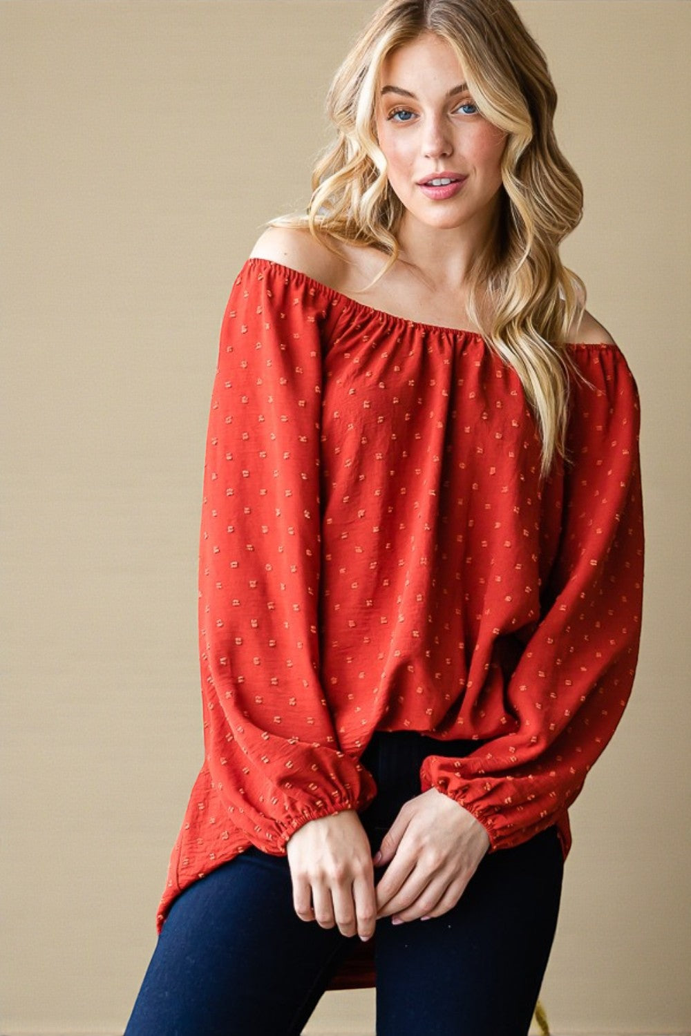 Woman wearing a red off-shoulder blouse with a beige background