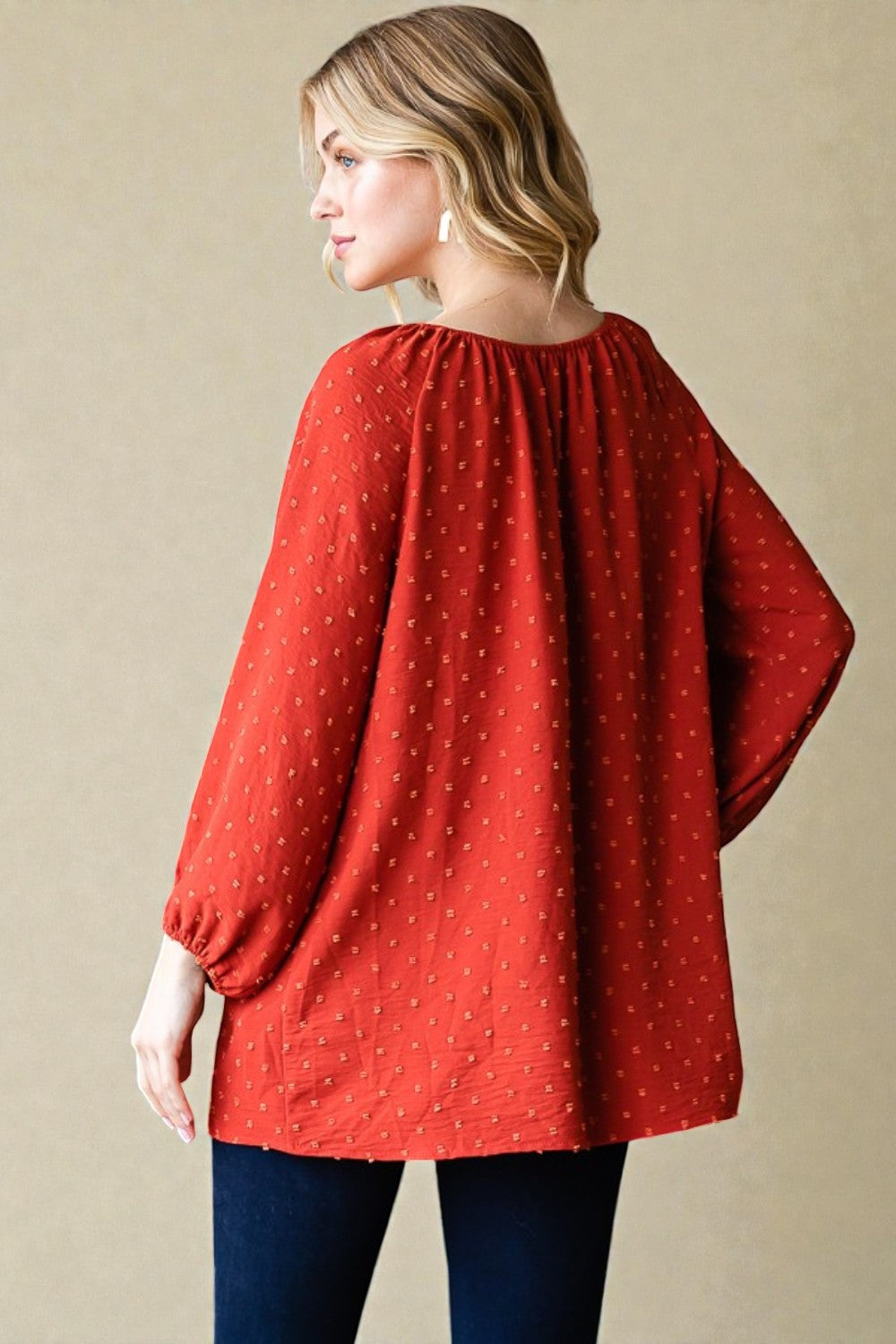 Woman wearing a red blouse with long sleeves on a beige background