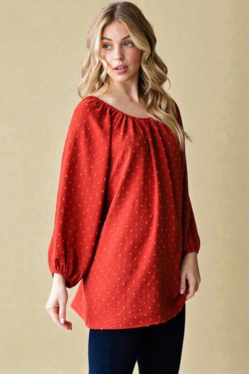 Woman wearing a red polka dot blouse against a beige background