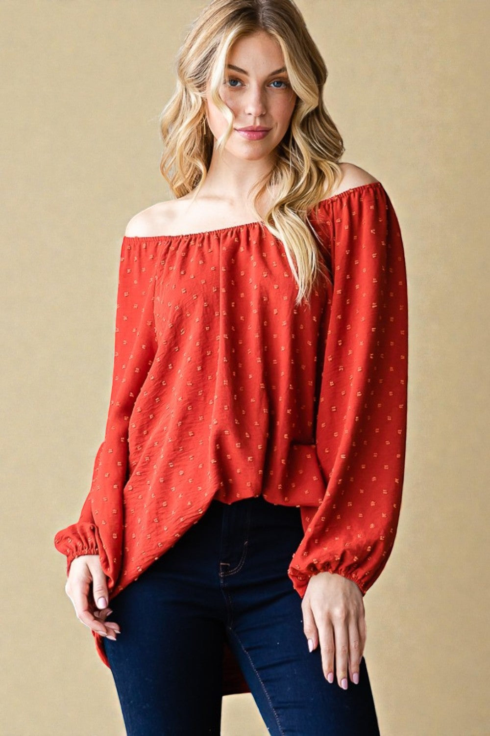 Woman wearing a red off-shoulder blouse against a beige background