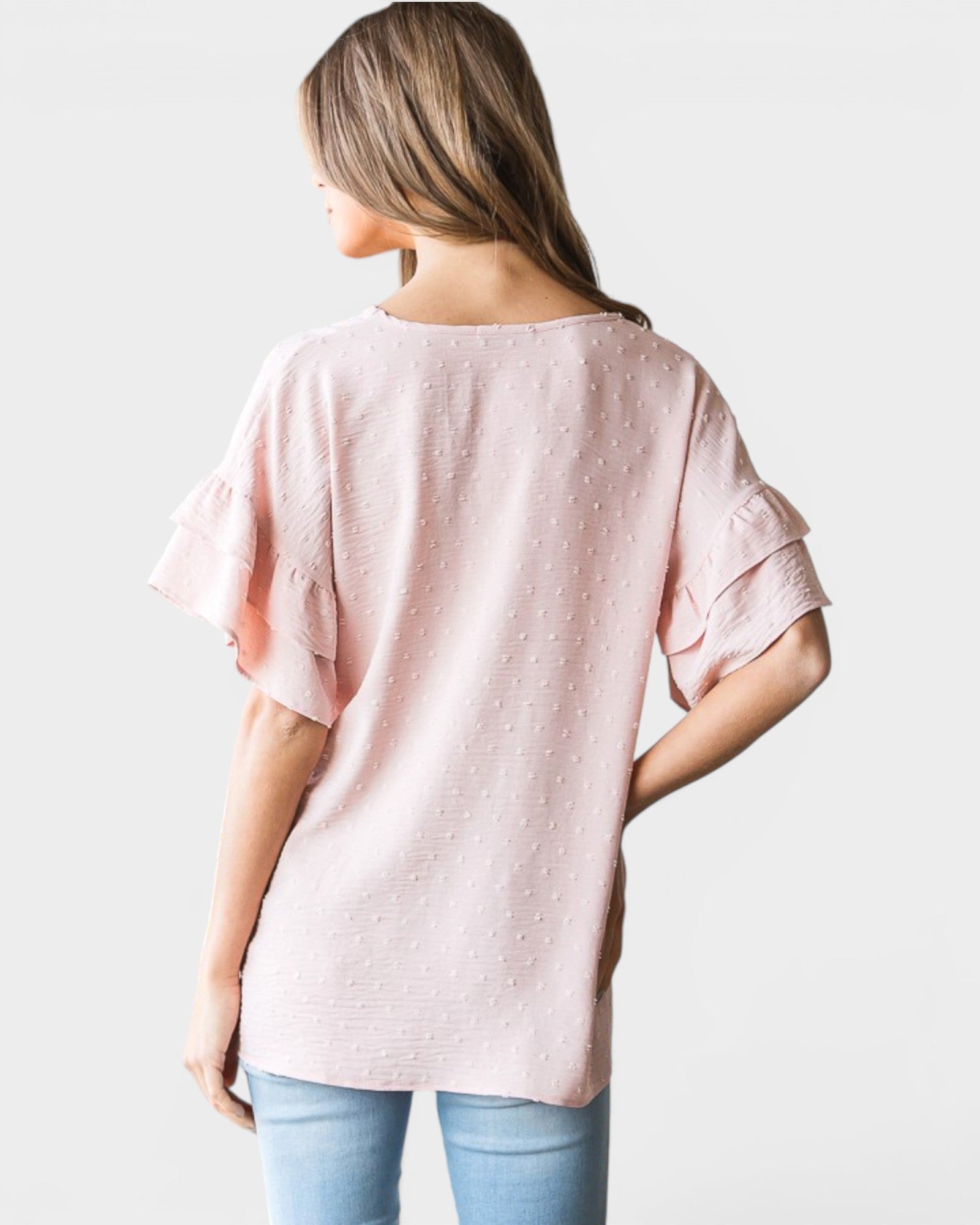 Woman wearing a light pink blouse with short sleeves on a plain background