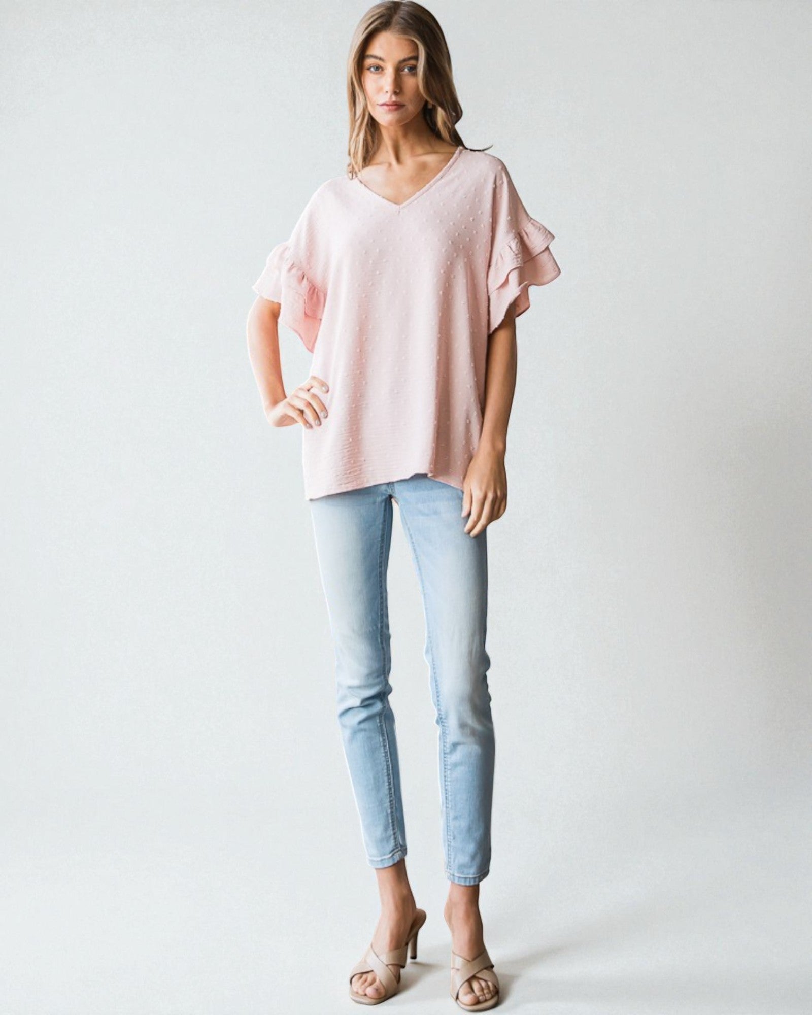 Woman wearing a pink top and light blue jeans on a white background