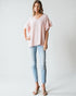 Woman wearing a pink top and light blue jeans on a white background