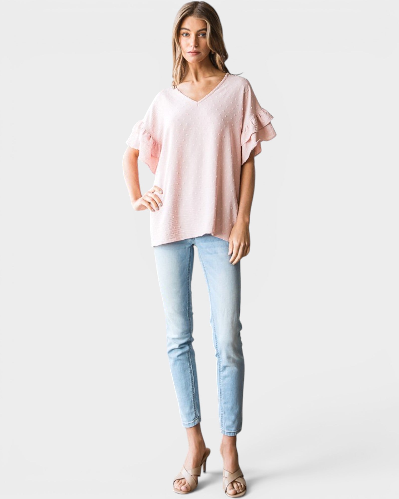 Woman wearing a pink top and light blue jeans on a white background