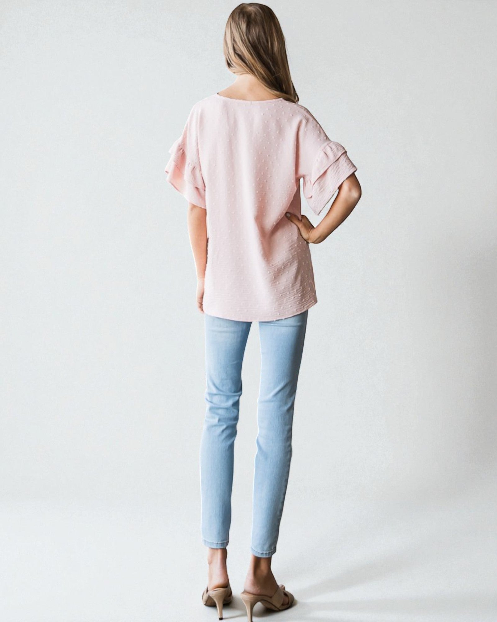 Person wearing a light pink blouse and light blue jeans on a white background