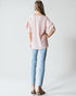Person wearing a light pink blouse and light blue jeans on a white background