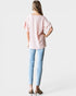 Woman wearing a light pink blouse and light blue jeans on a white background