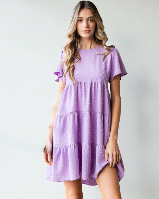 Woman wearing a purple dress against a plain background