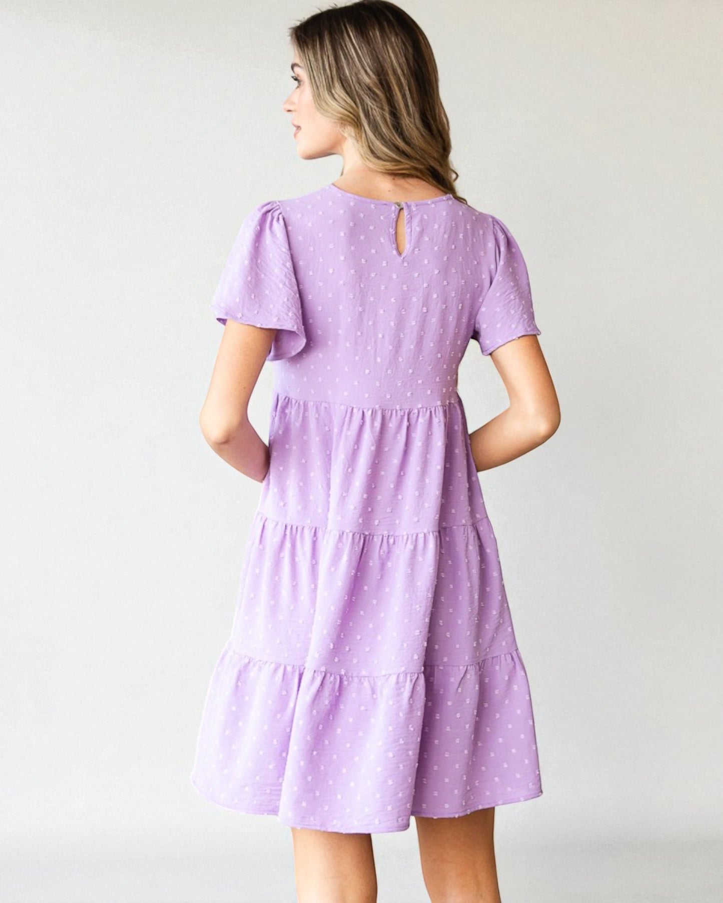 Woman wearing a purple dress against a plain background