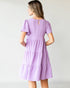 Woman wearing a purple dress against a plain background