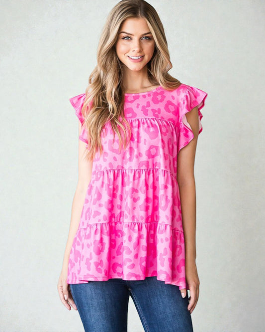 Woman wearing a pink leopard print top with blue jeans on a plain background