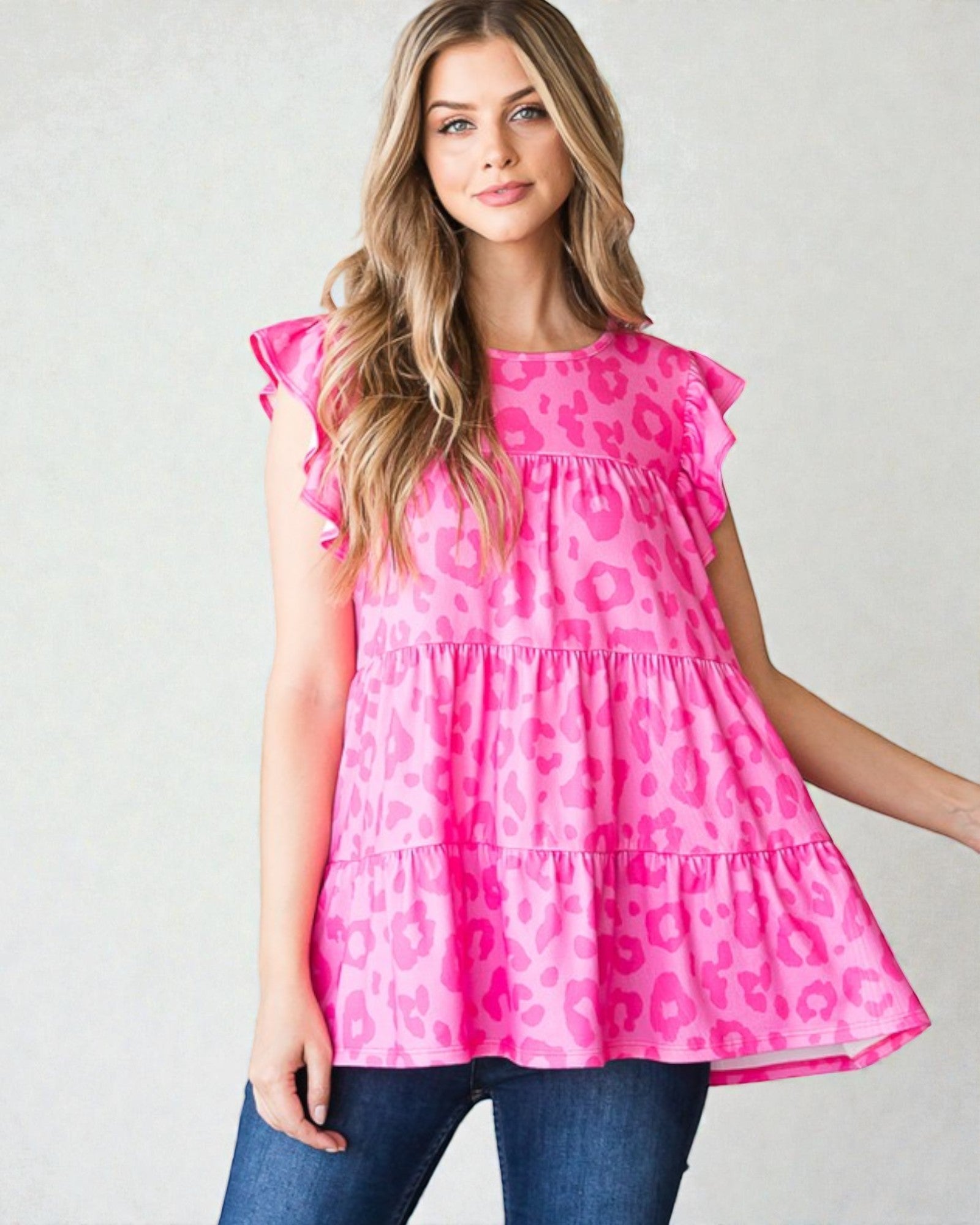 Woman wearing a pink leopard print top against a plain background