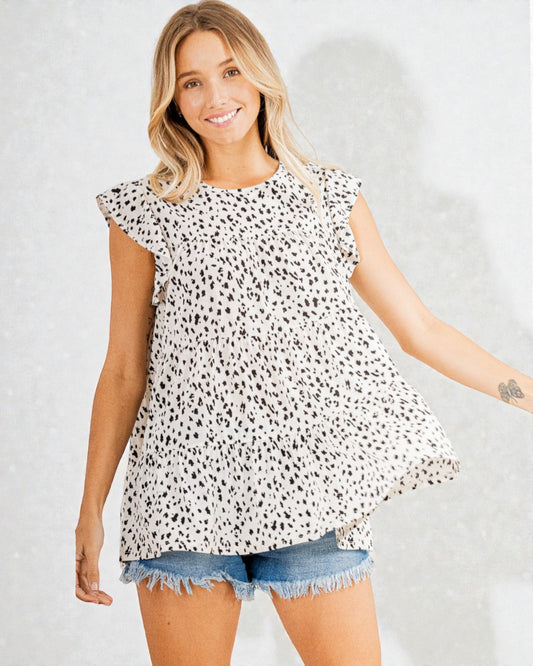 Woman wearing a black and white patterned top with denim shorts on a plain background