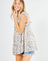 Woman wearing a sleeveless polka dot top and denim shorts on a light gray background