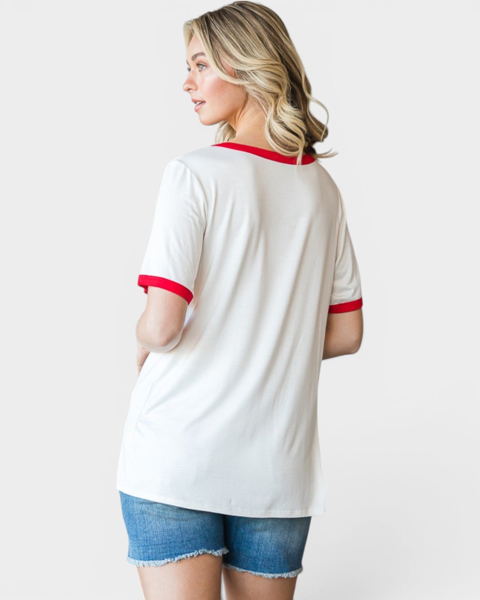Woman wearing a white t-shirt with red trim and denim shorts on a plain background