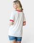 Woman wearing a white t-shirt with red trim and denim shorts on a plain background