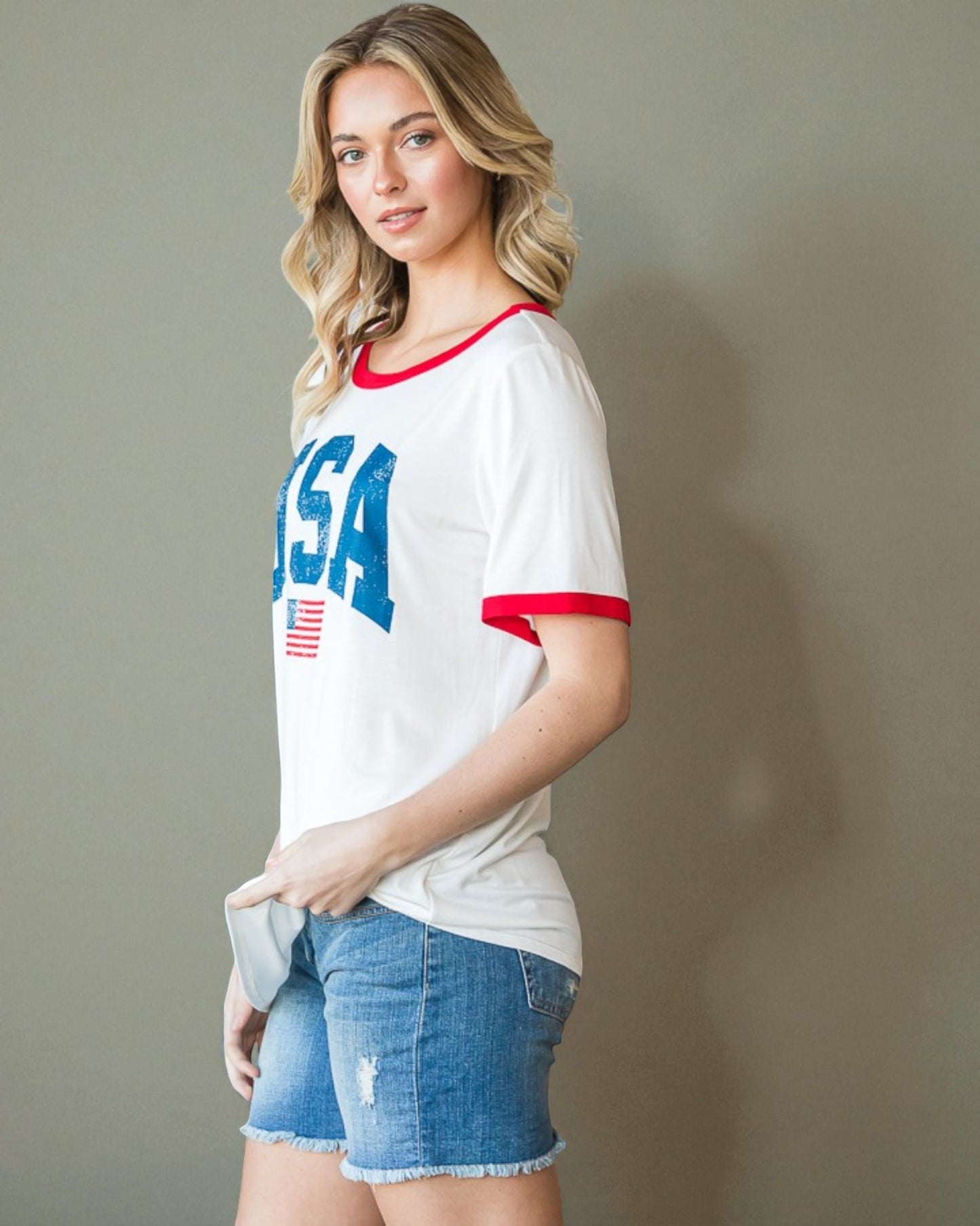 Woman wearing a white t-shirt with 'USA' printed on it against a plain background